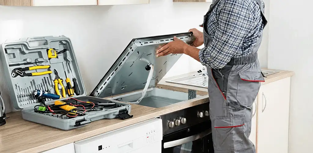 Handyman repairing a cooktop and checking wiring connections in Lowell, MA