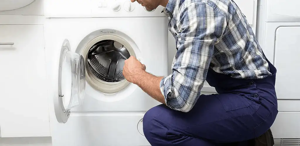 Handyman inspecting a dryer drum and internal parts for repair in Lowell, MA