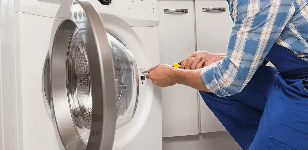 Handyman repairing a clothes dryer and checking electrical connections in Lowell, MA