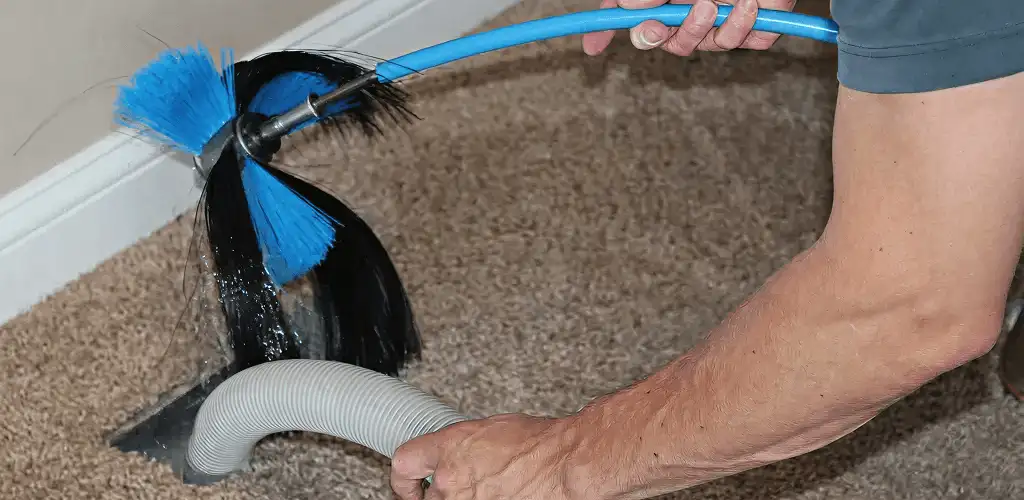Dryer vent cleaning technician brushing lint from a vent line in Lowell, MA