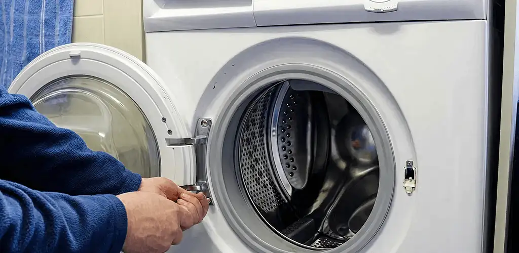 Washing machine repair handyman checking a front-load washer door and latch in Lowell, MA