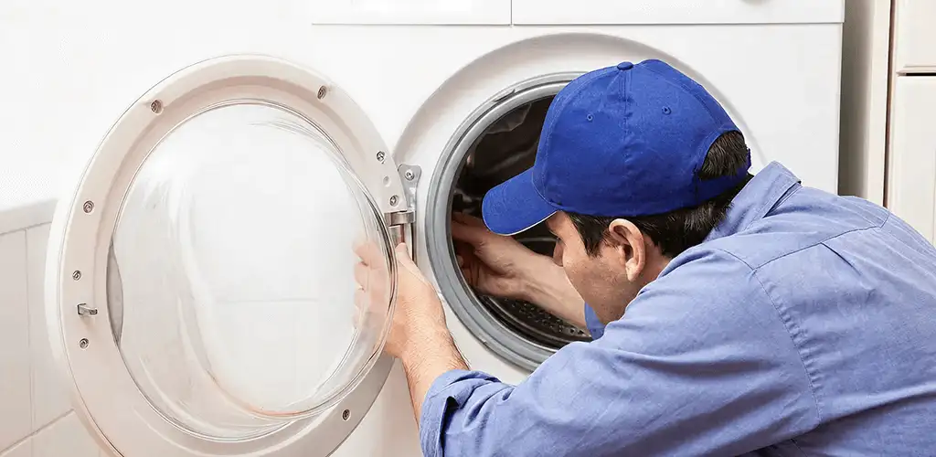 Washing machine repair handyman inspecting a front-load washer drum in Lowell, MA