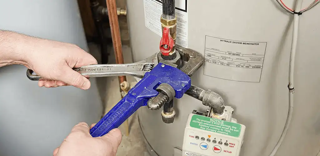 Water heater repair technician tightening the shutoff valve and supply line in Lowell, MA